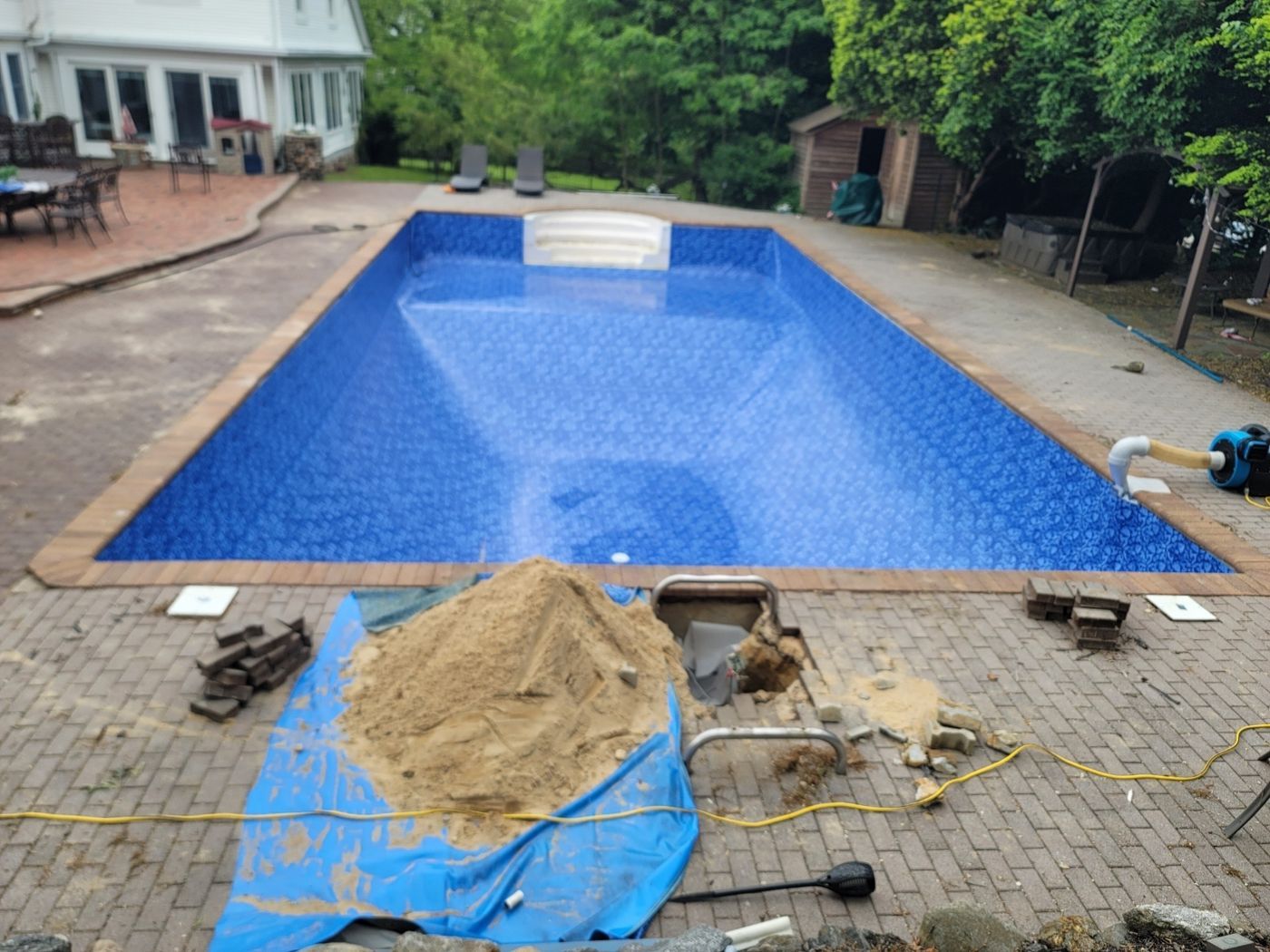 A rectangular pool with a brand new blue liner, filling with water