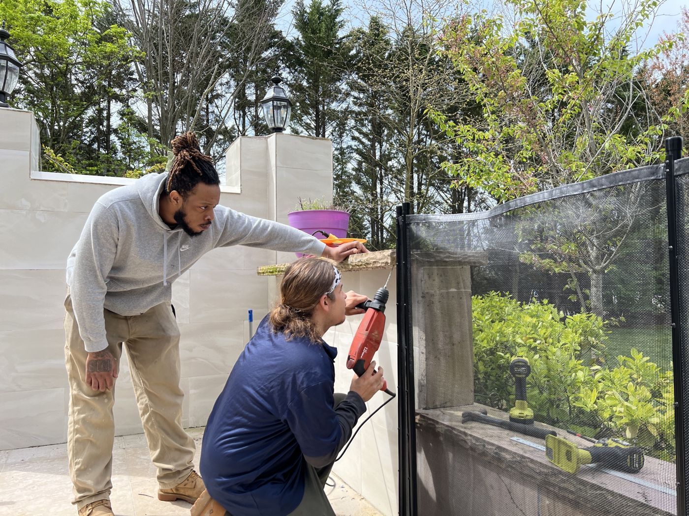 Two techs drilling and mounting a removable mesh pool fence