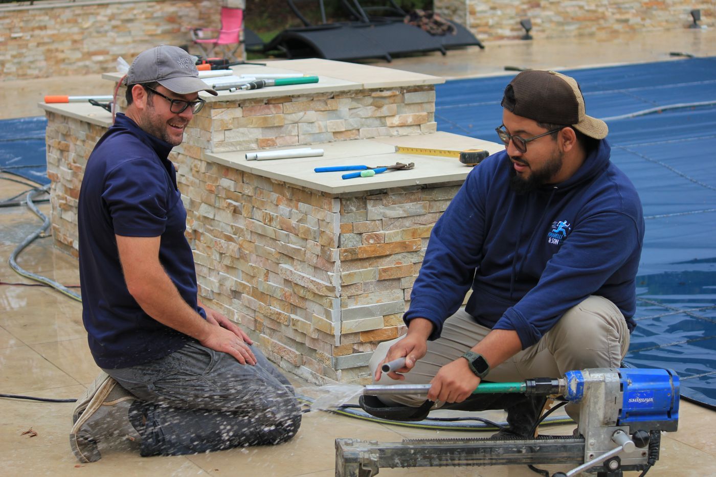 Two techs fitting a safety cover around a stone bar