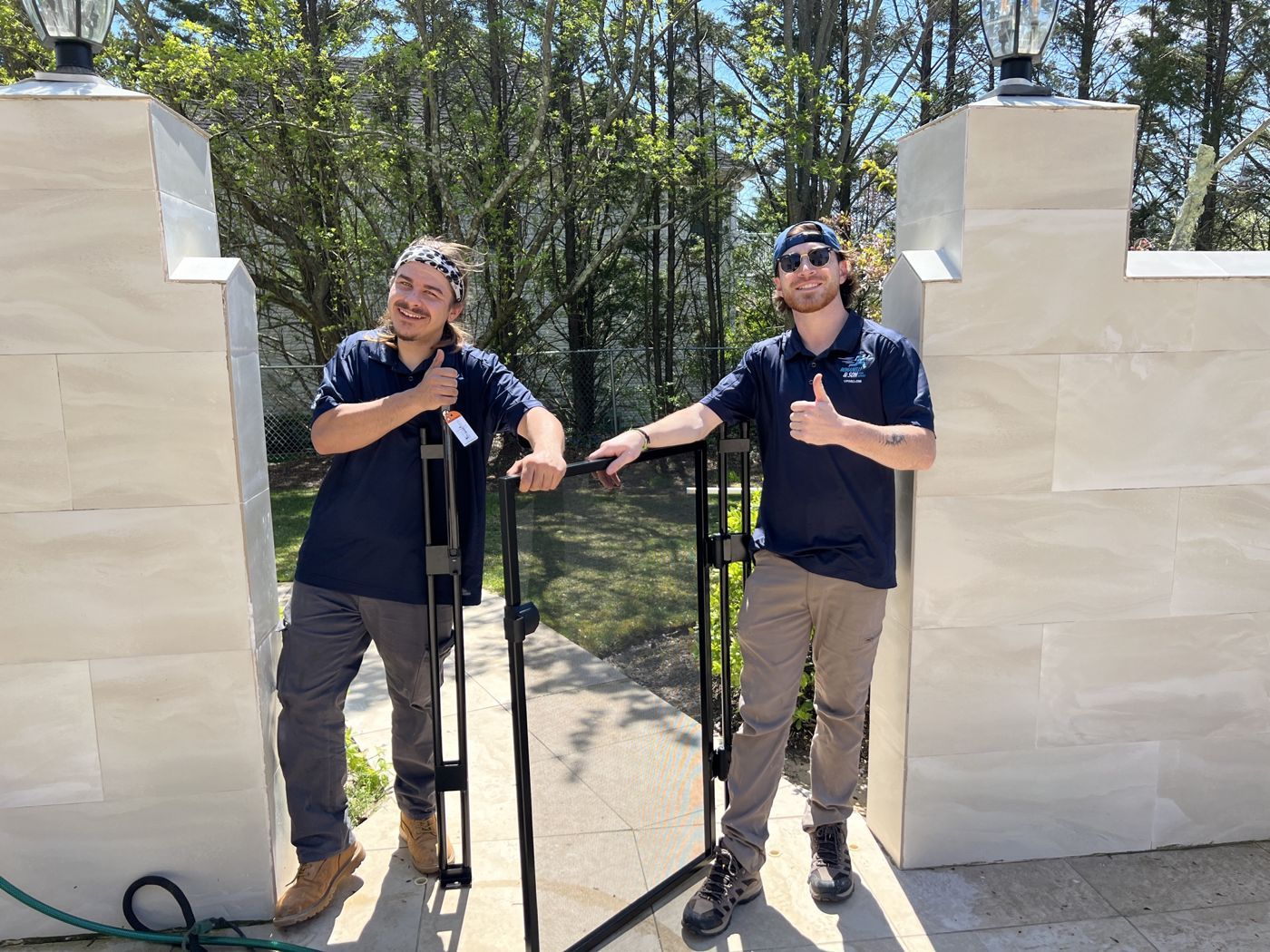 Two Romanelli techs smiling beside a finished pool fence