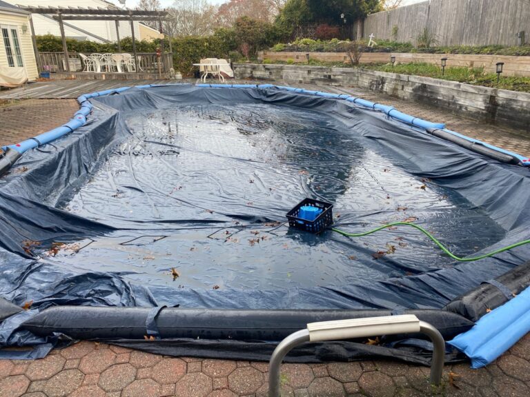 Cover pump running on a solid winter pool cover with water bags around the edge